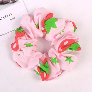 Detail of pink fabric scrunchie featuring cute red strawberry patterns and green leaves