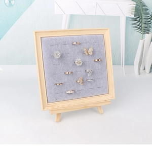 Detail of wooden jewelry display rack with grey velvet lining showing multiple rings