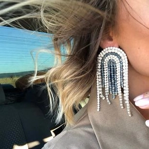 Detail of oversized skull tassel earrings with white and blue rhinestones on model