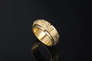 Macro shot of rotatable gold dragon ring with embossed pattern on black background