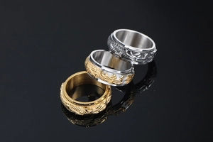 Detail of spinning stainless steel rings with gold and silver dragon relief patterns