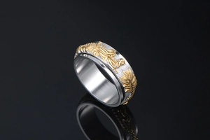 Detail of a rotating dragon relief ring in gold and silver stainless steel