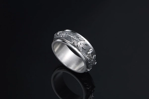 Macro shot of silver punk spinner ring featuring intricate dragon relief and vintage finish