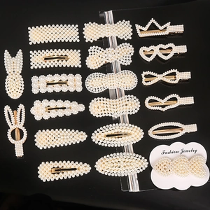 Flat lay of multiple pearl hair clip designs including bows and hearts on gold bases