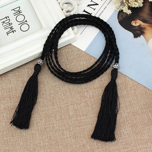 Ethnic style black braided waist rope with metal accents and tassels on linen background