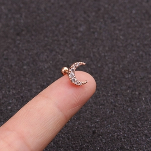 Rose gold crescent moon cartilage stud earring with cubic zirconia held on a fingertip