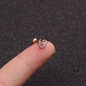 Close-up of rose gold star and moon stud earring with zircons held on a fingertip
