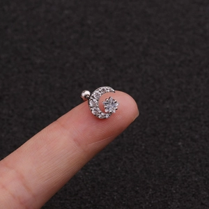 Minimalist silver moon and star stainless steel stud earrings with zircon held on fingertip