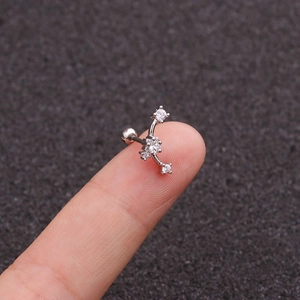 Macro view of curved silver stainless steel ear bone stud with white zircon on finger