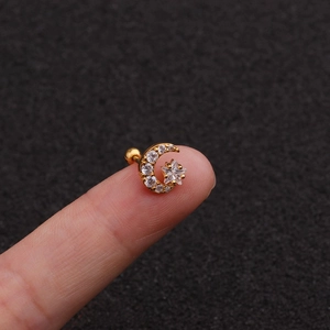 Macro detail of gold star and moon stud earring with white zircon and screw back