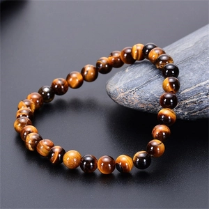 Detailed macro view of natural tiger eye stone beads with golden cat-eye effect on a rock