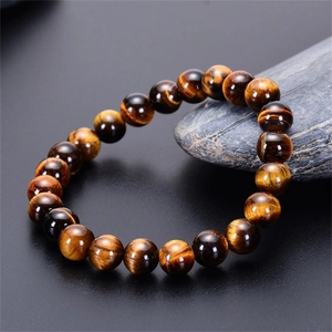 Macro shot of natural yellow tiger eye stone beads bracelet on dark stone background