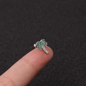 Silver coconut tree stud earring with green and white cubic zirconia on finger