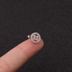 Detailed close-up of a silver flower stud earring with zircon inlay held by fingers