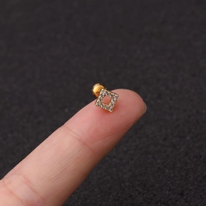 Detail of square gold stud earring with clear zircon inlay held on fingers