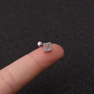 Macro shot of a silver square zircon stud earring on fingertip showing size and detail