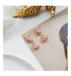 Pink cherry blossom earrings with golden mesh wrapped beads on a decorative prop background