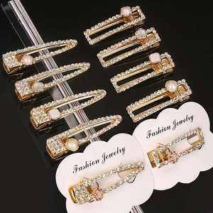 Detail of 9-piece gold hair clips set with sparkling rhinestones and pearls on black background
