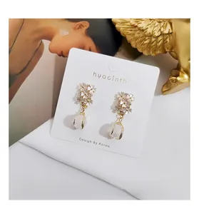 Detailed shot of vintage shell flower earrings with a pearl drop pendant on white card