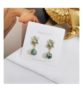 Detail of vintage flower drop earrings featuring green beads on a hyacinth display card