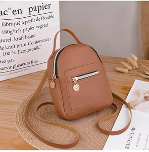 Brown leather mini backpack on a rustic wooden desk with aesthetic dried flower background