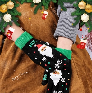 Close-up of Christmas knit gloves with Santa pattern and HO! text embroidery details