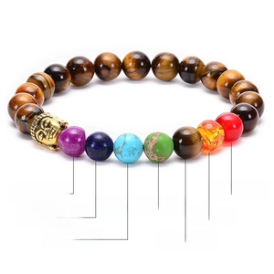 Chakra gemstone bracelet with tiger eye beads and golden Buddha head on white background