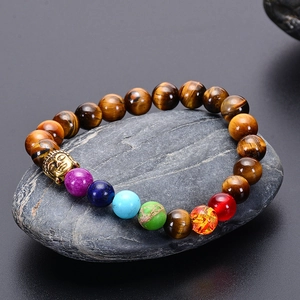 Macro detail of tiger eye chakra bracelet with golden buddha head on grey stone