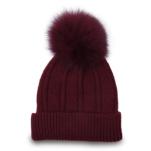Detailed view of the ribbed knit texture and fluffy burgundy faux fur pompom on the beanie