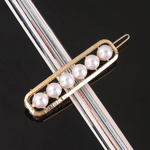Macro detail of gold-plated hair clip featuring six polished pearls and a snap closure