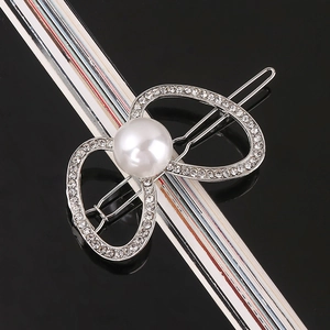 Silver bow hair clip with a large white pearl and sparkling rhinestones close-up
