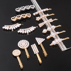 Macro view of assorted gold and silver hair clips with pearls on a black background