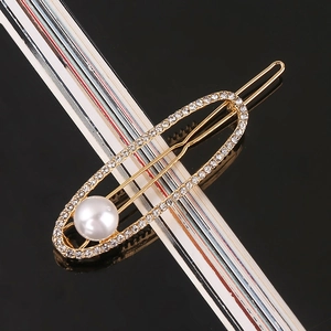 Detail shot of golden hair clip with large faux pearl and sparkling rhinestone border