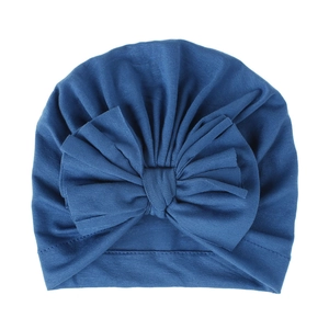 Vista ravvicinata di un cappello a turbante blu per neonati in cotone a maglia con fiocco.
