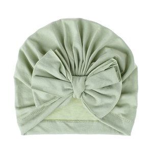 Turbante per neonati verde menta in morbida maglia con grande fiocco decorativo su fondo bianco