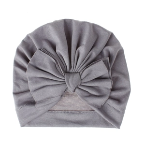 Dettaglio di un cappello a turbante grigio per neonati con un grande fiocco morbido
