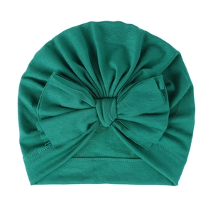 Dettaglio cappello turban neonato verde scuro con grande fiocco e trama a pieghe
