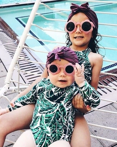 Bambini con eleganti turbanti viola a fiocco e occhiali da sole a fiore rosa in piscina