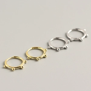 Macro detail of silver and gold minimalist bead ear cuffs in polished finish