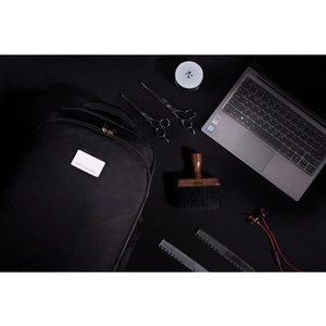 Detail of professional black barber backpack with gold zippers and grooming tools display
