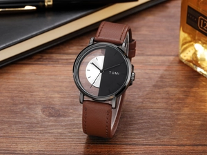 Close-up of TOMI quartz watch with dual-tone dial on a wooden desk with office stationery