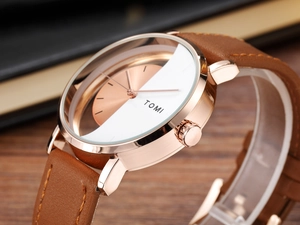 Close-up of rose gold TOMI quartz watch with brown leather strap on wooden surface