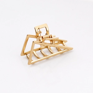 Close-up of golden metal triangle hair claw clip with durable spring on white background