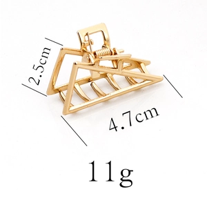 Detail of golden geometric hair claw clip with dimensions 4.7cm x 2.5cm and 11g weight