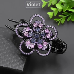 Detail of flower hair clip with purple rhinestones on a textured black base