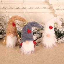 Three plush Christmas gnomes with heart hats and long beards on pine branches