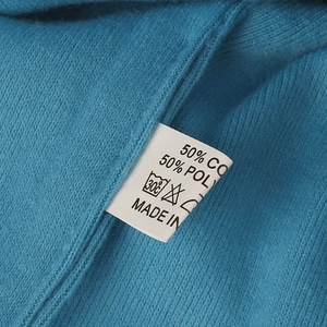 Dettaglio dell'etichetta con 50% cotone e 50% poliestere sul berretto in maglia blu
