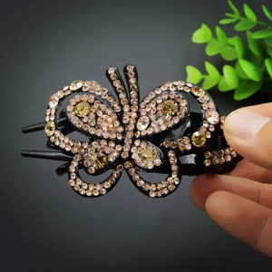 Detail of butterfly hair clip featuring amber rhinestones on a resin duckbill base