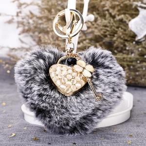 Plush heart keychain with cat eye stone pendant and four-leaf clover charm on a stand