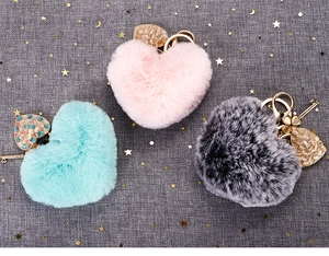 Detailed view of plush heart keychains with cat eye leaf charms in pink, blue, and gray